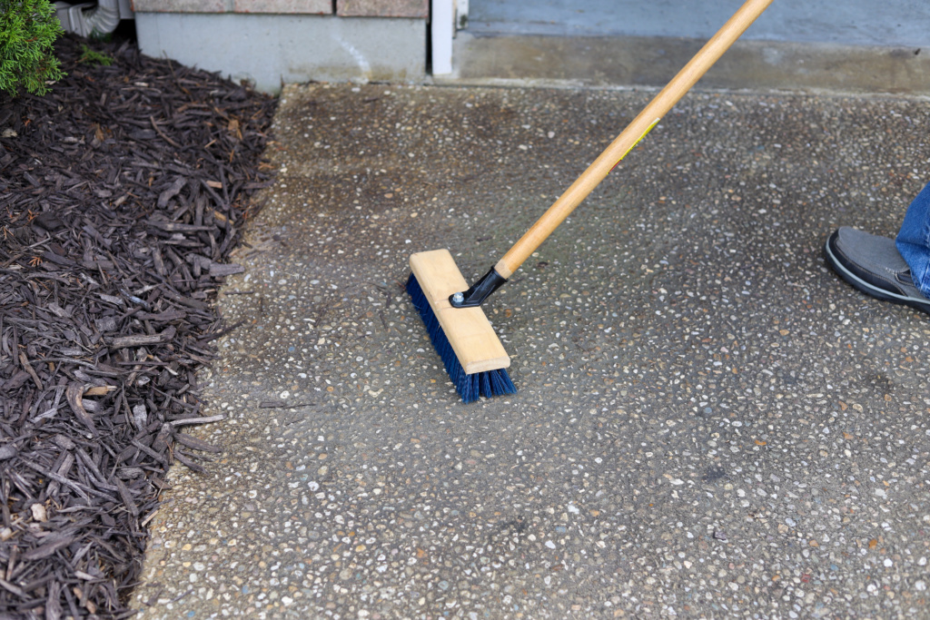 Man cleaning driveway space to clean a tarp